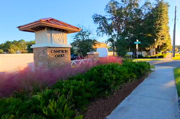 HOA community entrance monument framed by ornamental grasses and manicured shrubs